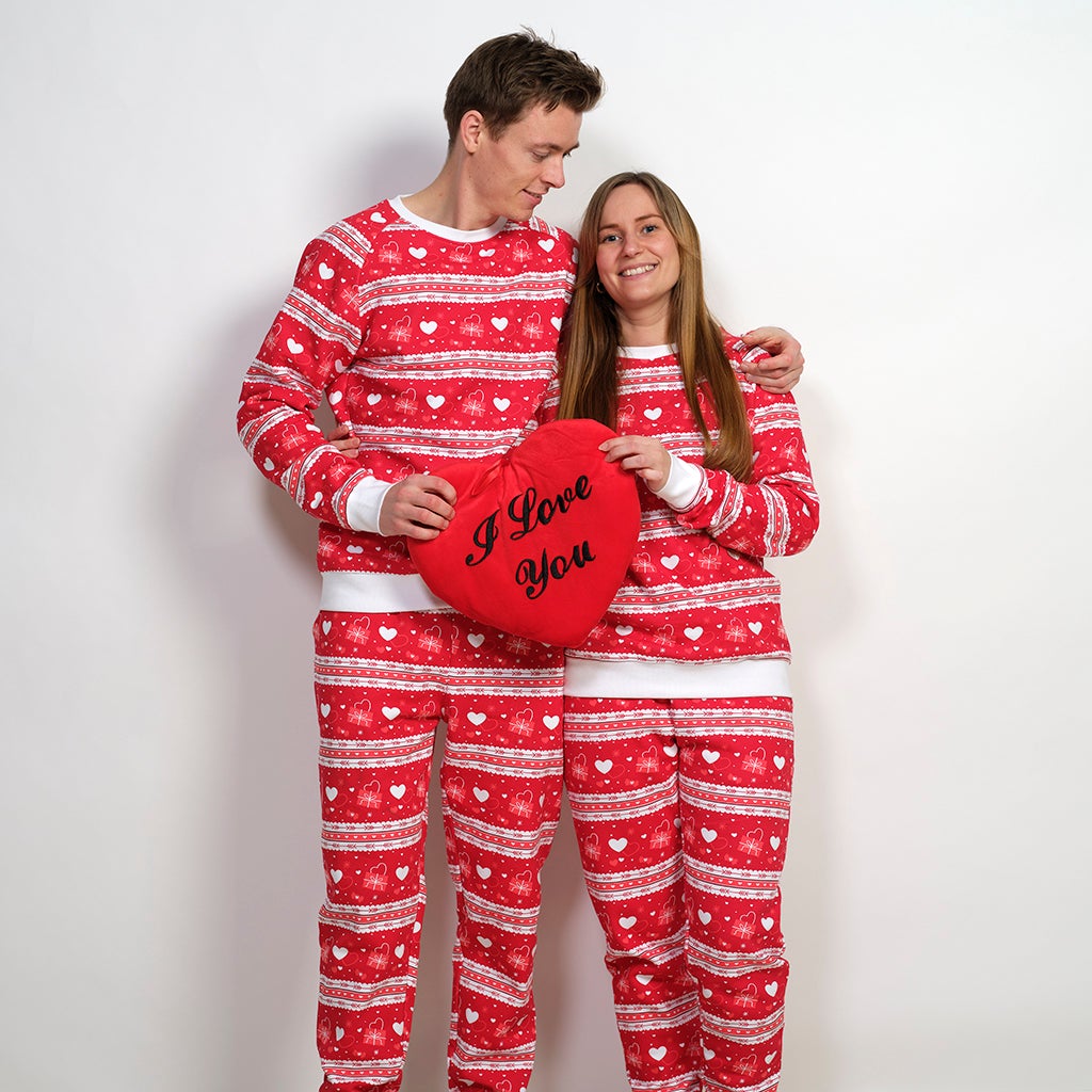 Una coppia che si abbraccia indossando un pigiama rosso con un motivo a cuore.